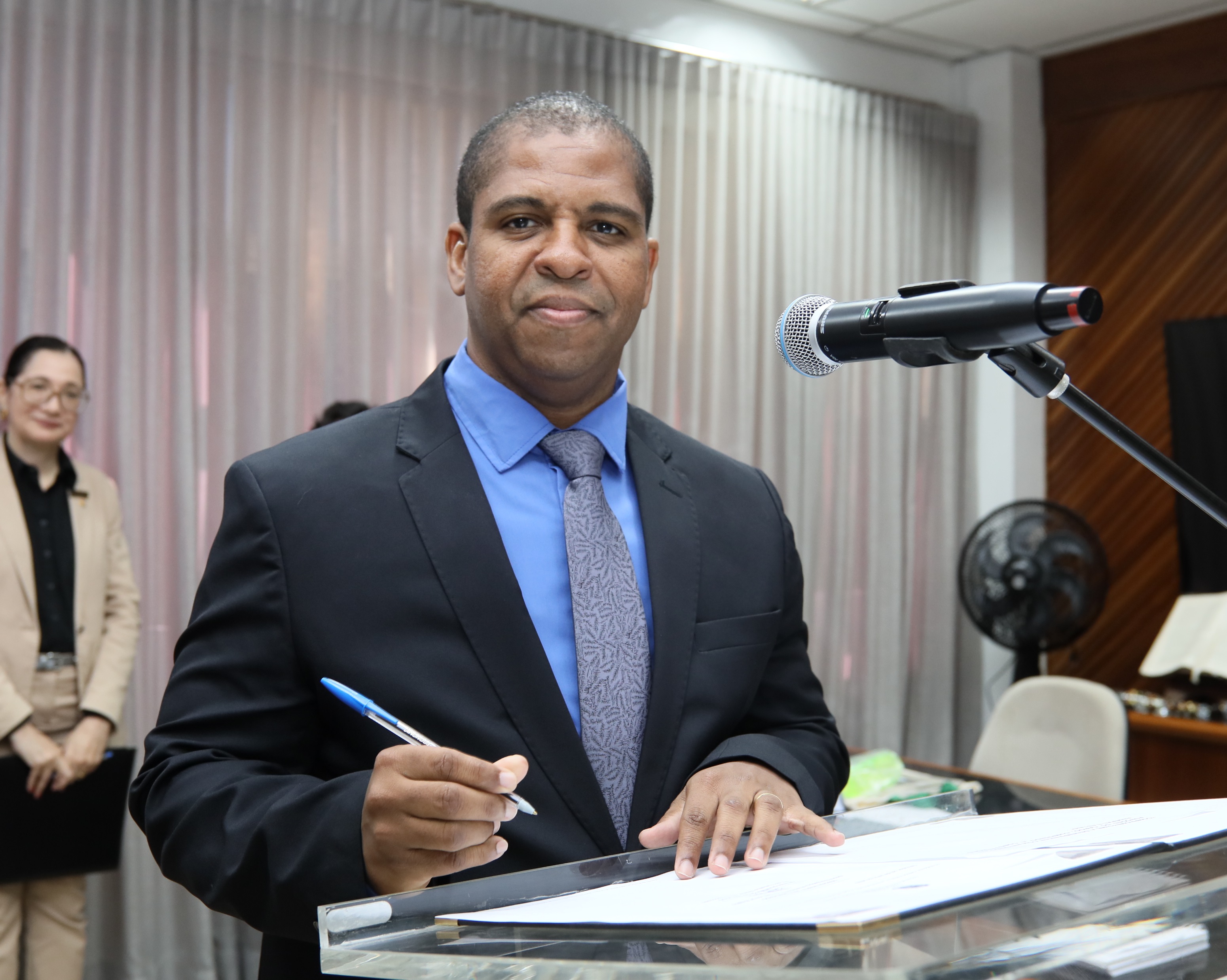 O juiz Gilvan Oliveira Silva Azevedo, homem negro de terno e grava azul, assinando o termo de posse como titular da Vara do Trabalho (VT) de Bom Jesus da Lapa