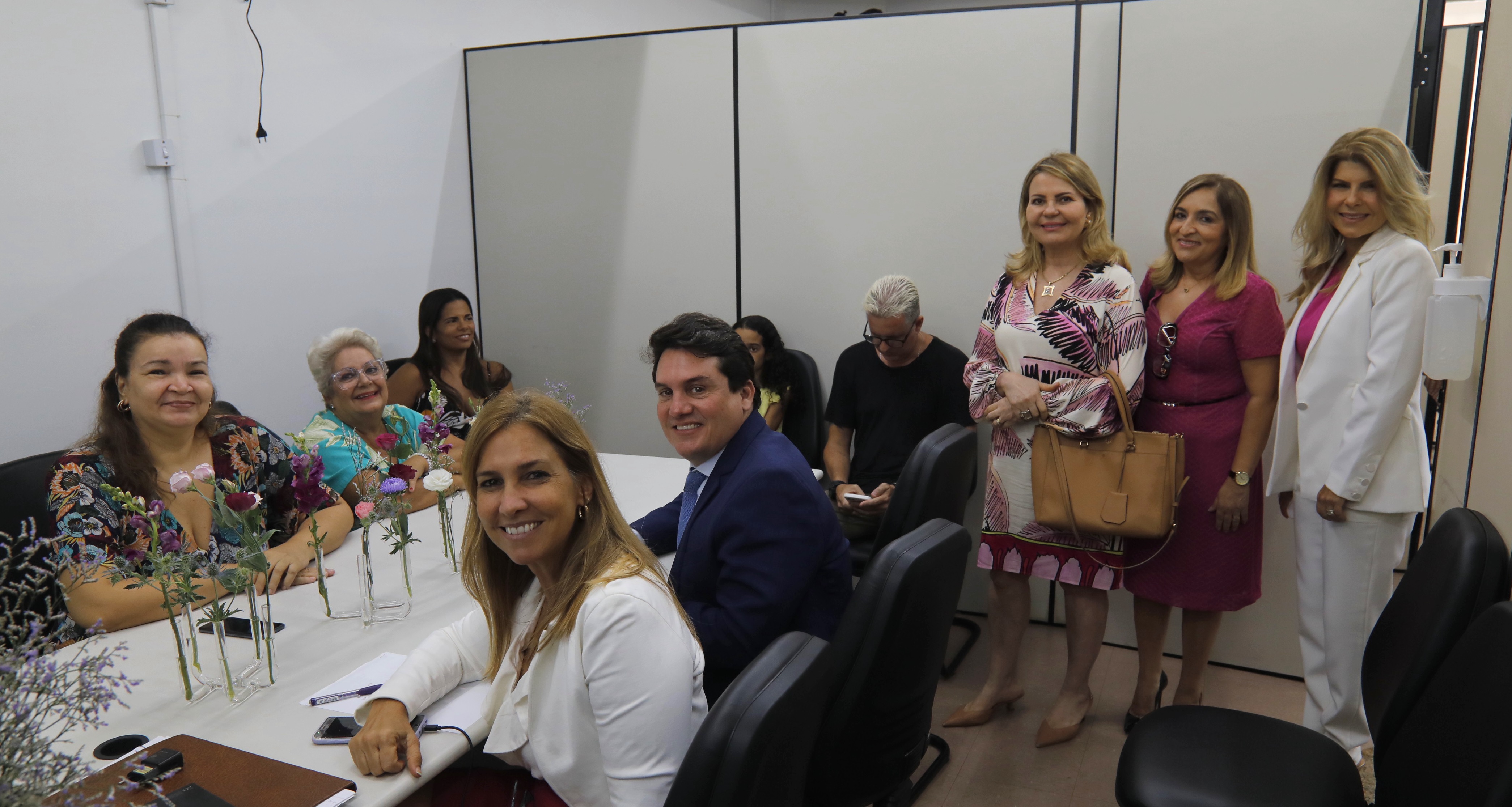 Desembargadoras Eloína Machado e Suzana Inácio observam, junto da juíza Mônica Sapucaia, a mesa de audiência de conciliação. À mesa estão advogados e as partes. 